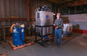 Johnny Davis holds a jar of the finished waste oil-based fuel created by his mini-biorefinery.&nbsp;
