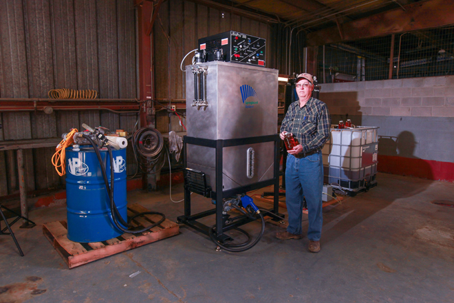 Johnny Davis holds a jar of the finished waste oil-based fuel created by his mini-biorefinery.&nbsp;