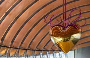 Jeff Koons' Hanging Heart (Gold/Magenta) is now suspended from the ribbed ceiling of one of the Crystal Bridges' glass-walled bridges.