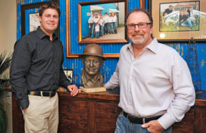 Grant, left, and his father, Alan Pruitt, right, pose with a sculpture of A.B. &ldquo;Buddy&rdquo; Pruitt, the founder of Pruitt Tool & Supply Co. | (Photo by Ryan Miller)