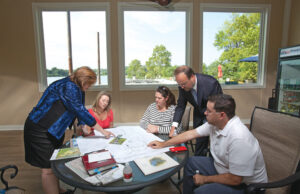 Lisa Ferrell and Jim Jackson, standing, of North Bluffs Development Corp., look over building plans with future Rockwater residents. Seated left to right: Ashley Russell, Michele and Wayne Hardy. | (Photo by Michael Pirnique)