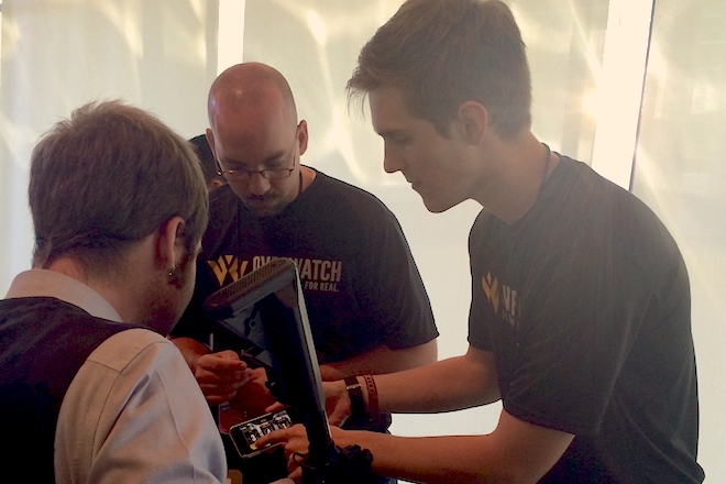 Michael Paladino (center) and Josh Moody (right) of Overwatch show off their product during ARK Challenge Demo Day at Crystal Bridges Museum of American Art in Bentonville. Overwatch was one of three winning teams from the 2013 ARK Challenge that presented an alumni update on Thursday.