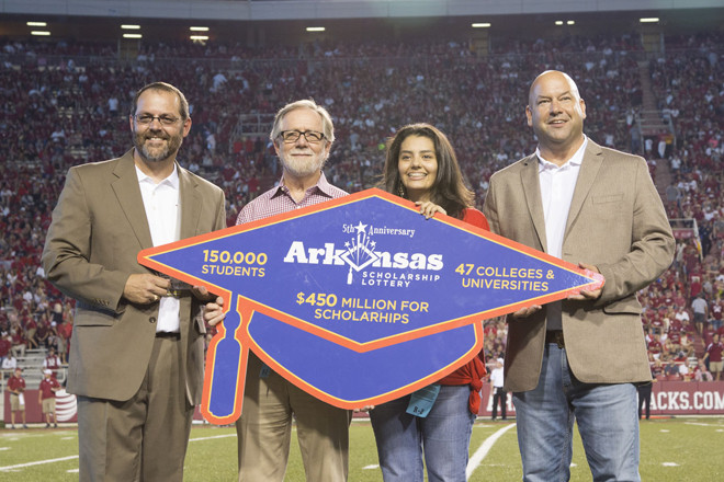 Nabil Tovar (center), an Academic Challenge Scholarship recipient who attends the University of Arkansas, participated in an on-field Arkansas Scholarship Lottery presentation with (from left to right) Daniel Pugh, vice provost for student affairs, Thomas Smith, dean of College of Education and Health Professions and Bishop Woosley, director of the Arkansas Scholarship Lottery during a football game at UA on Sept. 20. | (Photo courtesy of Arkansas Scholarship Lottery)