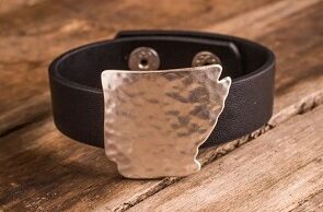 An example of the Bourbon & Boots by Dillard's line: a leather cuff with a silver plate fashioned in the shape of Arkansas.&nbsp;