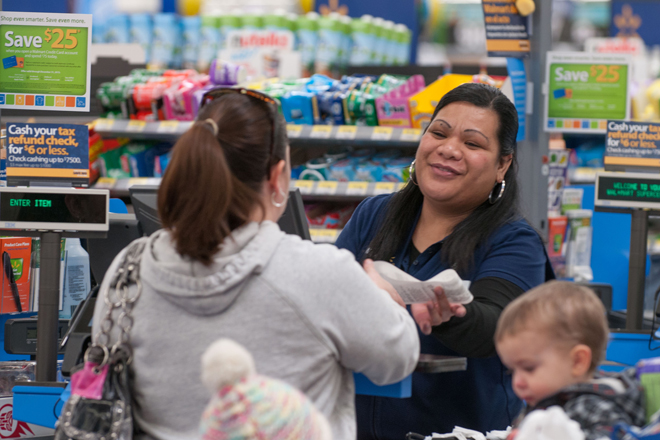 A Wal-Mart cashier helps customers check out at a store.