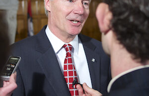 Asa Hutchinson talks to reporters after a news conference announcing Mike Preston as executive director of AEDC.