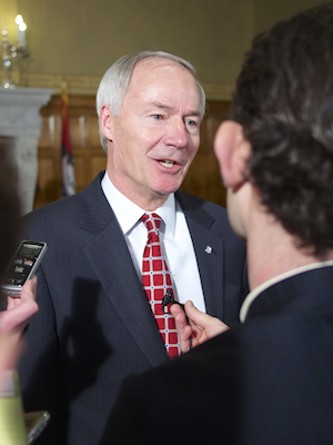 Asa Hutchinson talks to reporters after a news conference announcing Mike Preston as executive director of AEDC.