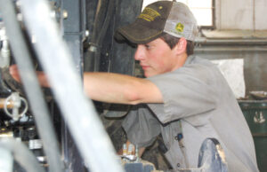 Ethan Patterson works on a tractor at the Greenway facility in Brinkley. Patterson, a Greenway employee, graduated the ASU-Beebe ag equipment technician program.
