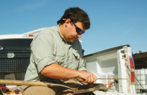 Isaac Davis, an agriculture major at Arkansas State University, sharpens a shovel on his family farm near Oil Trough.