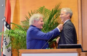 Home BancShares Chairman Johnny Allison places a lapel pin on Stonegate Bank CEO Dave Seleski as they announced their merger at the Little Rock Regional Chamber.