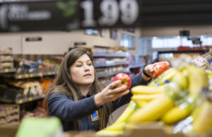An Aldi store employee stocks produce. The German-owned grocery chain has&nbsp;1,600 U.S. stores and is working aggressively to beat Wal-Mart on pricing.