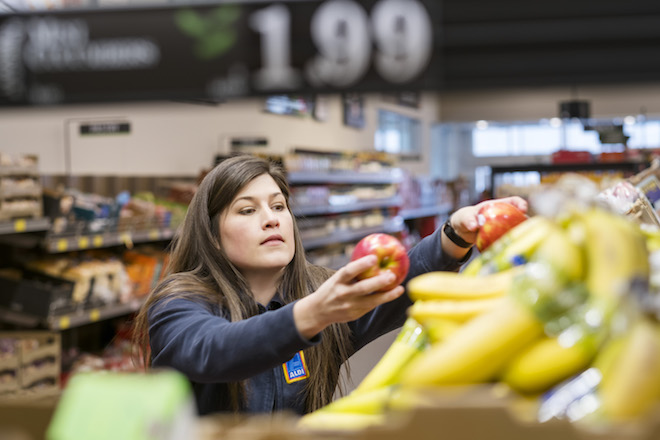 An Aldi store employee stocks produce. The German-owned grocery chain has&nbsp;1,600 U.S. stores and is working aggressively to beat Wal-Mart on pricing.