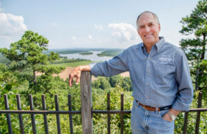 Shelby Woods, seen here on Pinnacle Mountain, has marketed Arkansas tourism for a half-century. One key has been the “Natural State” slogan he wears on his shirt.