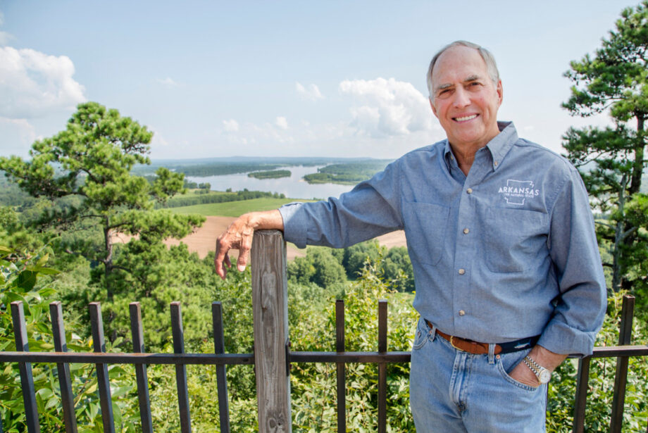 Shelby Woods, seen here on Pinnacle Mountain, has marketed Arkansas tourism for a half-century. One key has been the “Natural State” slogan he wears on his shirt.