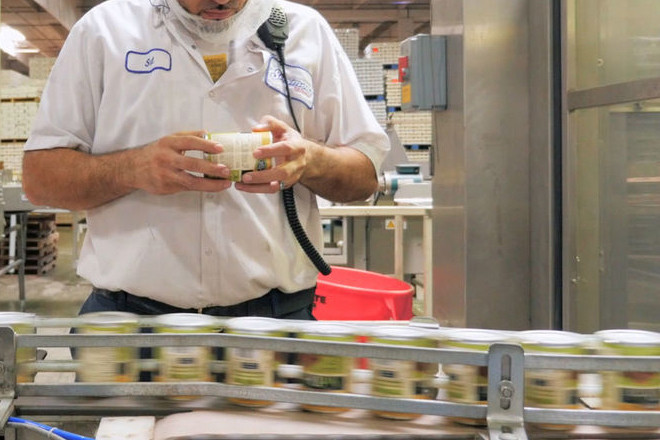 An employee of Simmons Foods monitors cans for inspection.