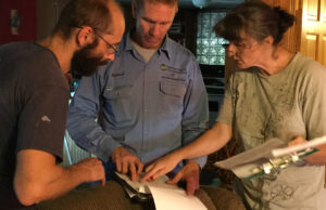 Richard Freeland (center) of Ouachita Electric Cooperative Corp. looks over an energy audit with Rafal and Agnieszka Olan of 3e Ark.