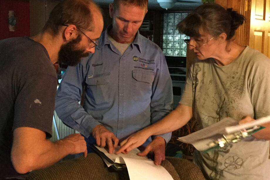 Richard Freeland (center) of Ouachita Electric Cooperative Corp. looks over an energy audit with Rafal and Agnieszka Olan of 3e Ark.