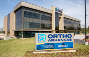 Signage at the newly opened OrthoArkansas Building reflects a pending merger that will create a 40-physician orthopedic group, the largest in Arkansas.