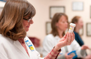A Walmart pharmacy associate inspects a vial of medication.
