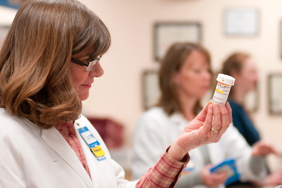 A Walmart pharmacy associate inspects a vial of medication.