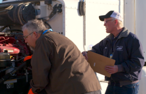 A new and veteran Walmart truck driver complete a pre-trip inspection.