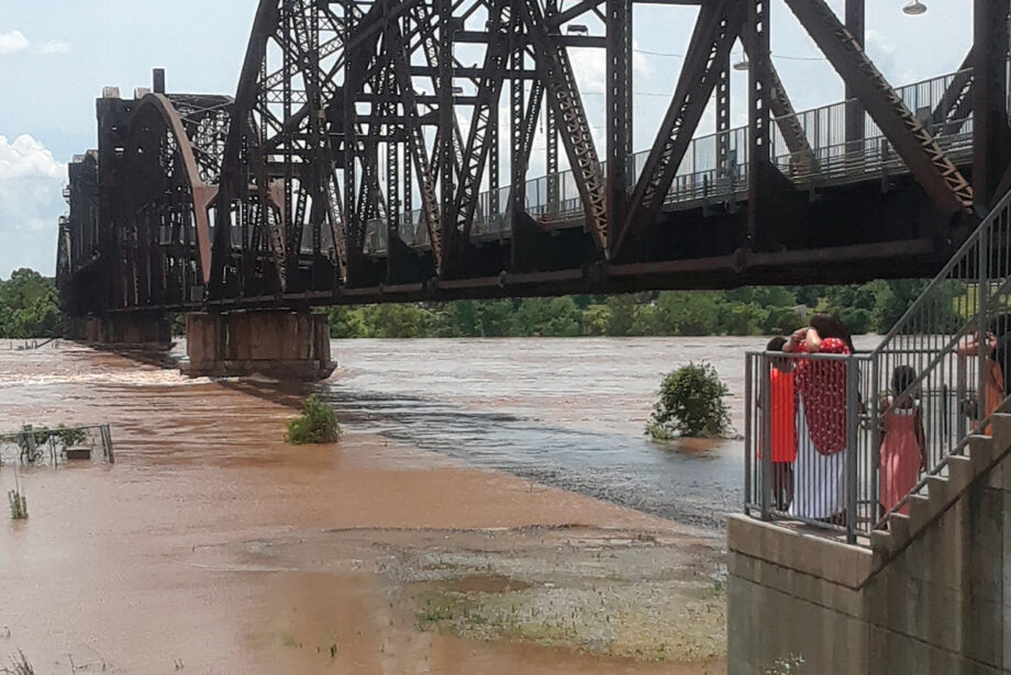 The Arkansas River rises against the Rock Island Bridge near the Clinton Presidential Center on June 2 as people watch from the north bank.