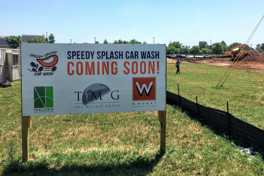 A sign at a construction site promotes a new Speedy Splash Car Wash location.