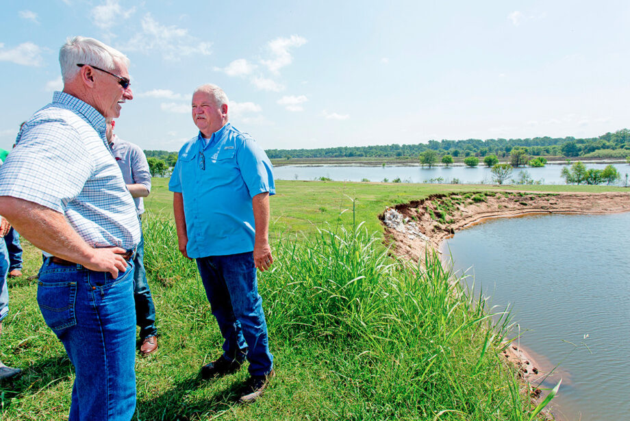 Arkansas Land Commissioner Tommy Land, in sunglasses, and Yell County Judge Mark Thone, in blue shirt, assess the damage along the Arkansas River near Dardanelle after the levee failed in the early morning  of May 31, flooding thousands of acres of farmland.