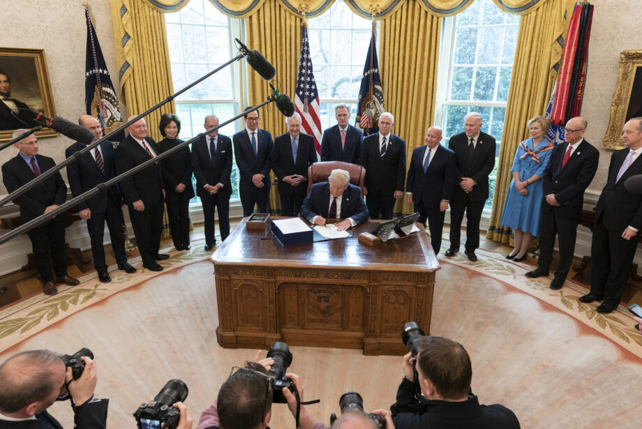 President Donald Trump, surrounded by federal health officials and Republican lawmakers, signed the&nbsp;Coronavirus Aid, Relief & Economic Security (CARES) Act on Friday.