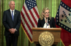 Stacy Hurst, secretary of the Arkansas Department of Parks, Heritage and Tourism, speaks Tuesday as Gov. Asa Hutchinson looks on during his daily coronavirus update news conference.