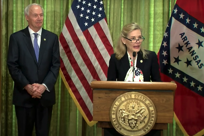 Stacy Hurst, secretary of the Arkansas Department of Parks, Heritage and Tourism, speaks Tuesday as Gov. Asa Hutchinson looks on during his daily coronavirus update news conference.