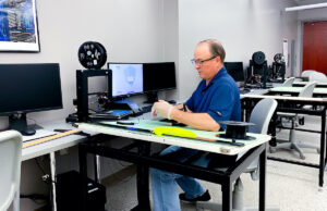 UAFS' Derek Goodson uses a 3-D printer to make a face shield component.