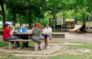 Picnickers enjoyed lunch last week in Allsopp Park while a nearby playground went unused. Park playgrounds in Little Rock, closed for most of the spring, were reopened on Friday.
