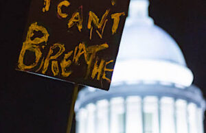 A protestor holds a sign during protests outside the state Capitol on Sunday. Little Rock Mayor Frank Scott Jr.&nbsp;re-instituted a nightly curfew on Monday.