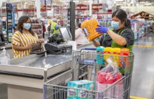 A Sam's Club customer and employee wear masks inside a store. Walmart Inc. of Bentonville says it will require customers to wear masks in all its stores and clubs across the country.