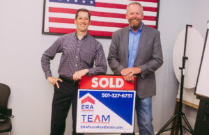 From left, Tom DeWine and Steve Doty pose with a sold sign to celebrate acquiring ERA Team Real Estate in Conway.