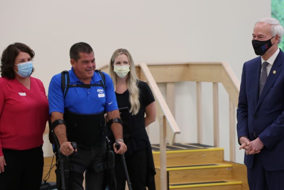 Joanna Weakley (left) with Eksobionics, the company that developed the device&nbsp;patient Jim Gratton is using here, and&nbsp;Kylie Daniels with Mercy accompany Gratton on tour of the new&nbsp;Mercy Rehabilitation Hospital Fort Smith on Friday. They were joined by Gov. Asa Hutchinson (far right).