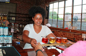 Black Apple cider tender Broox Piggee hands an order to customer Jody Burkett.