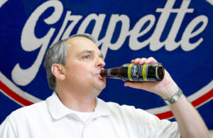 David Rice, vice president and director of marketing at Grapette International, tosses back a signature soda at the Malvern plant.