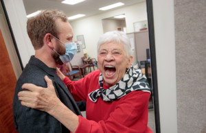 Mary Waldo, a former KUAR staff member, right, reacts in joy with UA Little Rock Public Radio General Manager Nathan Vandiver, left, after learning of a $1.5 million gift to the station.