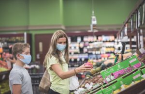 Chicago, IL- August 21, 2021:Mother and child wearing masks shopping at supermarket. Family wearing masks picking fruits at supermarket- pandemic concept for editorial use only