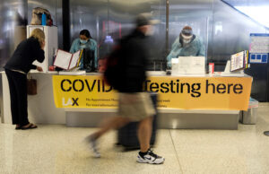 A traveler at Los Angeles International Airport walks past a COVID-19 testing site.&nbsp;