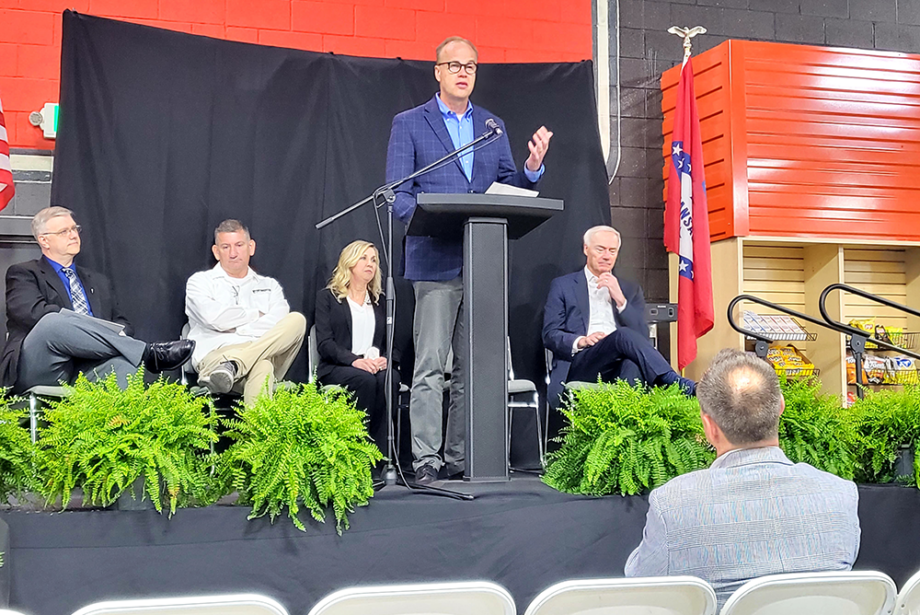 The Toro Company Chairman and Founder Rick Olson, behind the podium, speaks at an event in Batesville on April 21 celebrating the company's acquisition of Intimidator Group. Behind him, in a white shirt, is Intimidator Group founder Robert Foster.