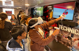 Students use a virtual reality headset at a station inside a "Be Pro Be Proud" mobile workshop
