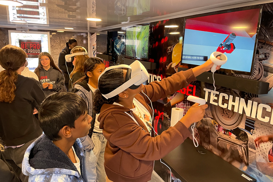 Students use a virtual reality headset at a station inside a "Be Pro Be Proud" mobile workshop