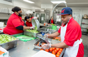 UAMS patient and nutrition services team member Maurice Jones Jr., far right, slices tomatoes as Jennifer Martin helps Latazanee Hatley wash freshly chopped romaine lettuce.