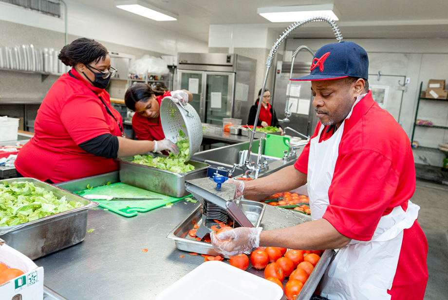 UAMS patient and nutrition services team member Maurice Jones Jr., far right, slices tomatoes as Jennifer Martin helps Latazanee Hatley wash freshly chopped romaine lettuce.