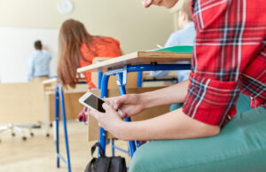 Student with cellphone on school classroom