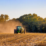 A tractor driving through a dry field.