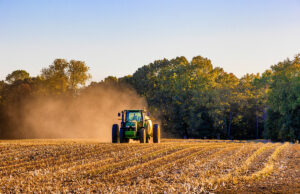 A tractor driving through a dry field.